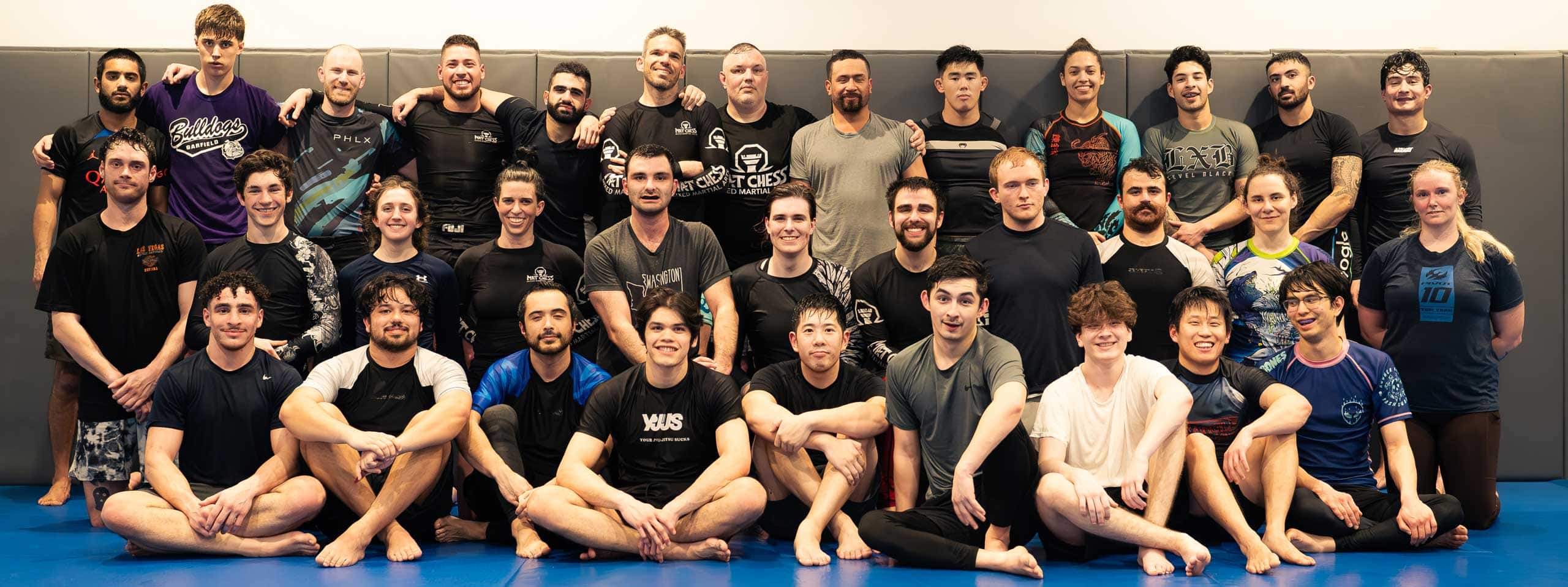 Large group of jiu-jitsu practitioners posing for a class photo on the mat